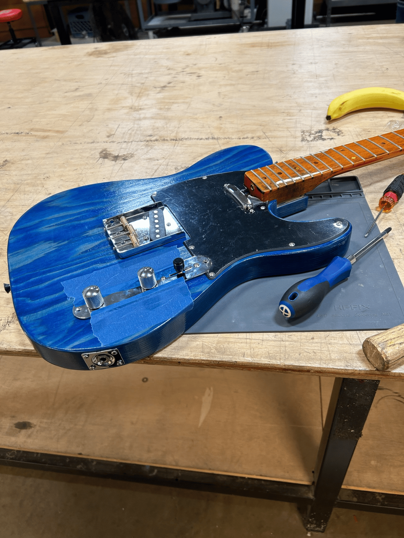 Fig. 5 · Bridge, pickup, control plate, and roasted-maple neck fitted into their routed positions, the signal path soldered into one harness before stringing to pitch.