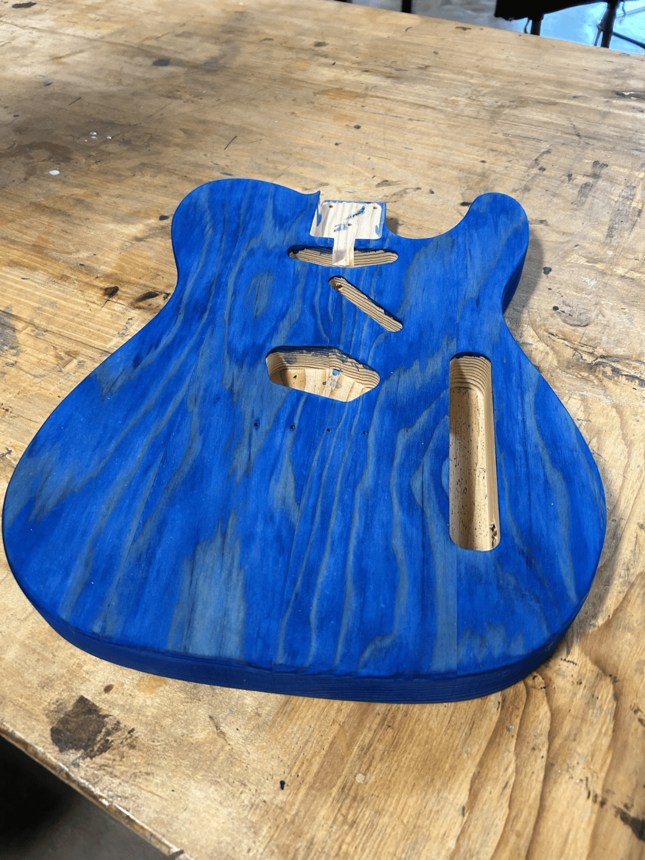 Fig. 3 · Hand-dyed blue over the routed cavities and neck pocket; the dye builds into the grain while the figure stays visible through the color.