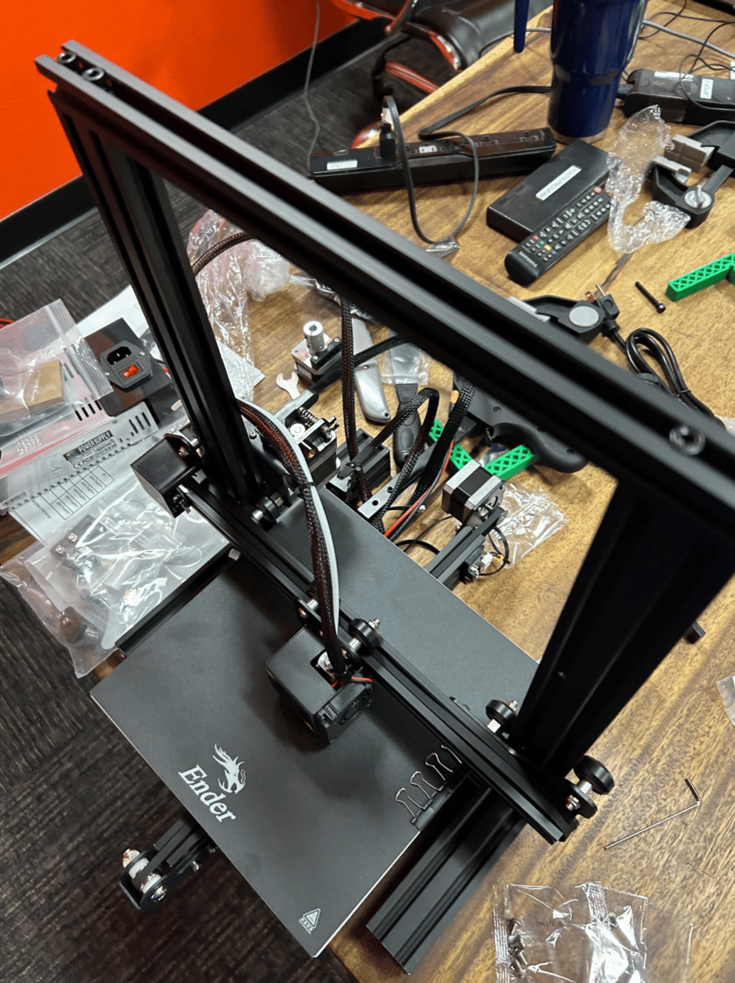 Fig. 1 · The assembly mid-build: aluminum extrusions, stepper motors, the gantry, and the loose hardware the machine reduces to.