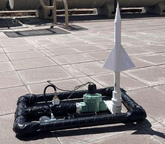 Fig. 1 · The finished paper rocket staged on the compressed-air launcher ahead of a trial.
